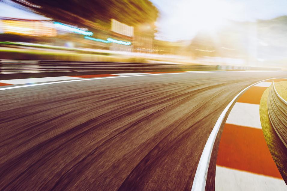 Kurvenabschnitt einer Rennstrecke mit unscharfem Hintergrund und farbigen Markierungen auf der Fahrbahn.