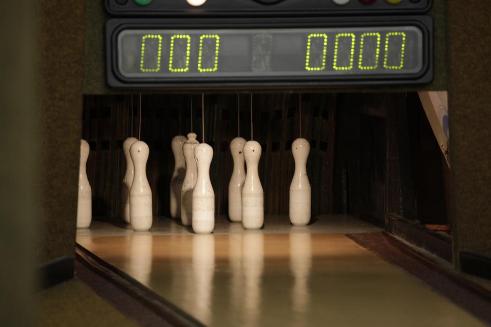 Nahaufnahme von Kegel auf einer Kegelbahn mit einem Punktestand-Anzeigegerät im Hintergrund.